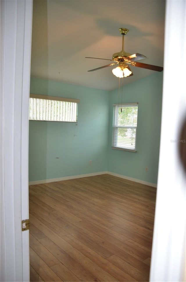 spare room with lofted ceiling, a ceiling fan, baseboards, and wood finished floors