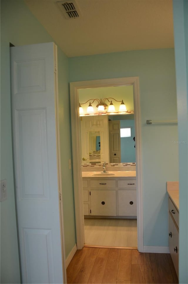 bathroom featuring baseboards, visible vents, wood finished floors, and vanity