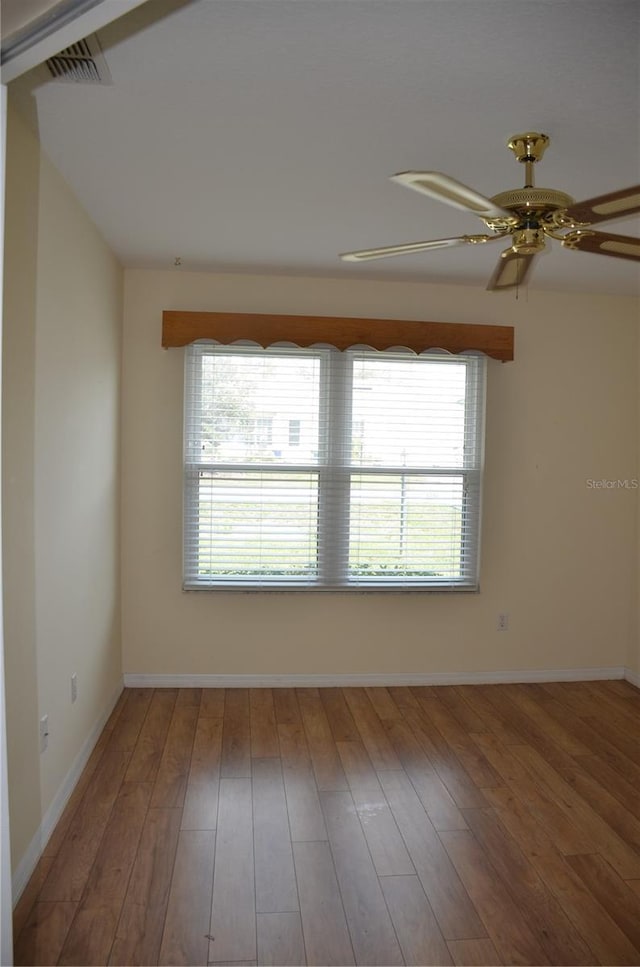 spare room with visible vents, wood finished floors, a wealth of natural light, and baseboards