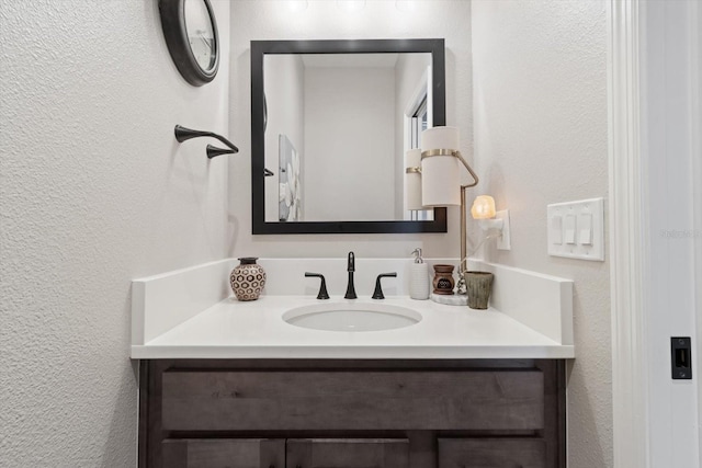 bathroom with a textured wall and vanity