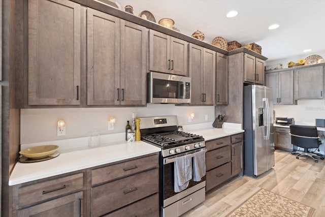 kitchen with appliances with stainless steel finishes, light wood-type flooring, light countertops, and recessed lighting