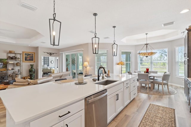 kitchen with visible vents, a raised ceiling, dishwasher, open floor plan, and a sink