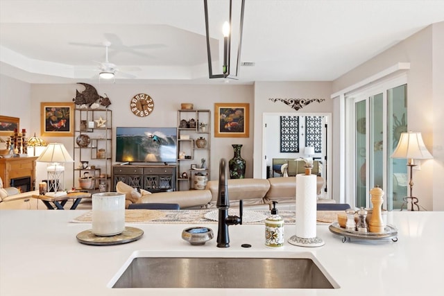 kitchen with a glass covered fireplace, a raised ceiling, a sink, and open floor plan