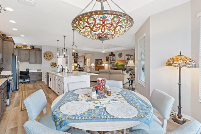 dining room featuring recessed lighting, visible vents, baseboards, light wood finished floors, and a tray ceiling