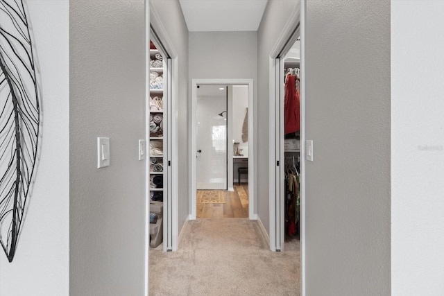 corridor featuring a textured wall and light colored carpet