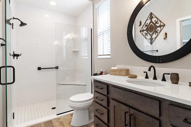 full bathroom featuring vanity, a shower stall, toilet, and wood finished floors