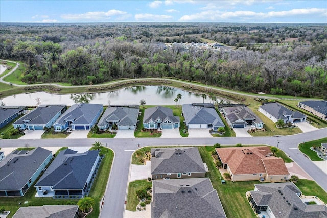 drone / aerial view featuring a forest view, a water view, and a residential view