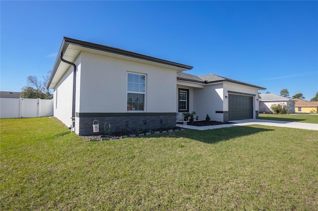 view of front of home with a garage, fence, driveway, stucco siding, and a front yard