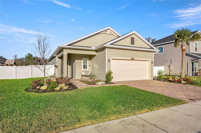 view of front of house with an attached garage, fence, decorative driveway, board and batten siding, and a front yard