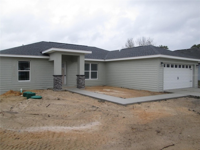 view of front of home featuring a garage and a shingled roof