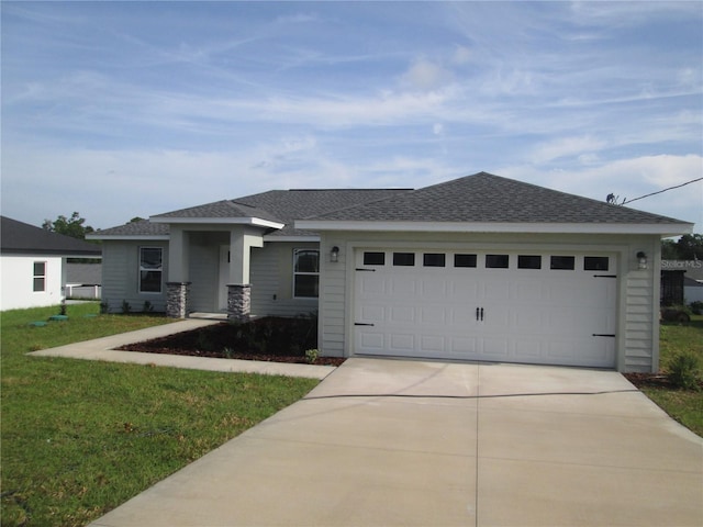 ranch-style house featuring a garage, roof with shingles, a front yard, and concrete driveway