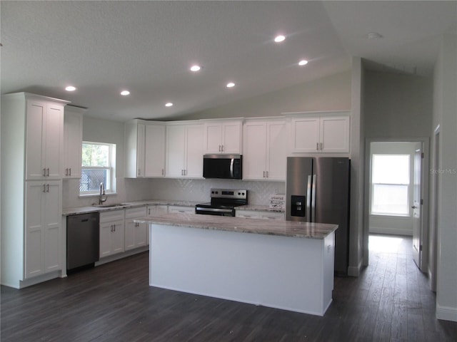 kitchen featuring a sink, white cabinetry, backsplash, appliances with stainless steel finishes, and a kitchen island