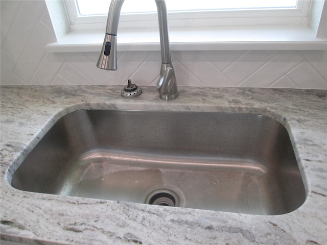 interior details featuring light stone counters, tasteful backsplash, and a sink