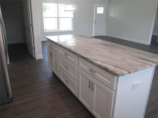 kitchen with white cabinets, dark wood-style floors, baseboards, light stone countertops, and a kitchen island