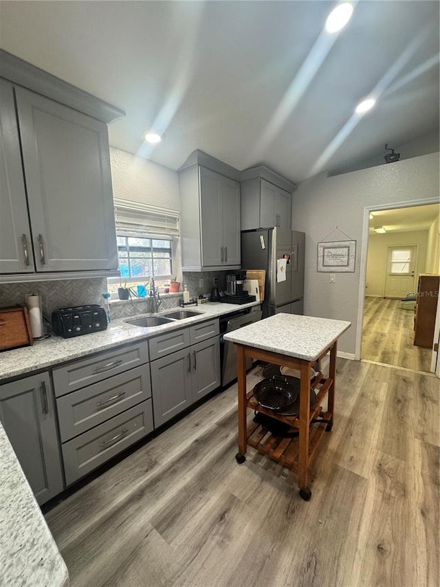 kitchen with black dishwasher, lofted ceiling, gray cabinetry, freestanding refrigerator, and a sink