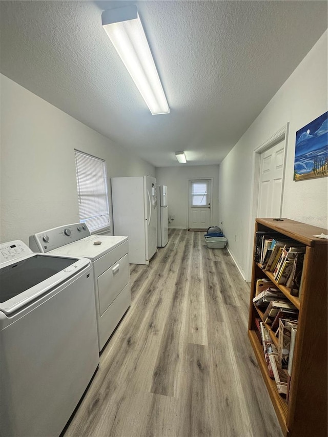 laundry room featuring light wood-style floors, laundry area, a textured ceiling, and washing machine and clothes dryer