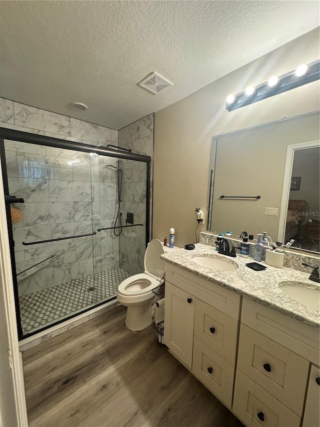 full bath with visible vents, a sink, a shower stall, and wood finished floors