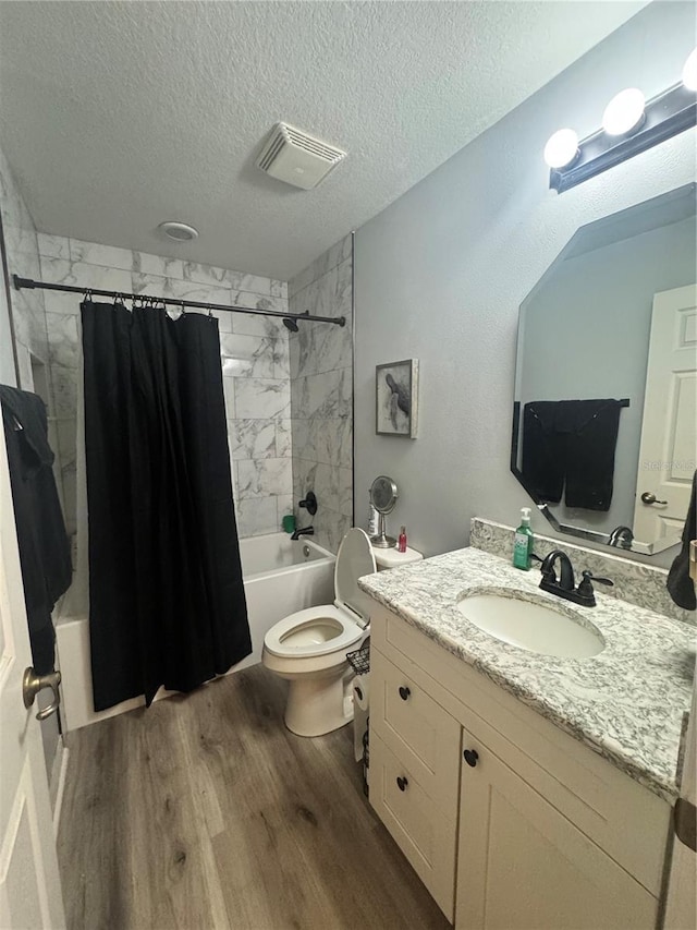 full bathroom featuring visible vents, shower / bath combo with shower curtain, a textured ceiling, vanity, and wood finished floors