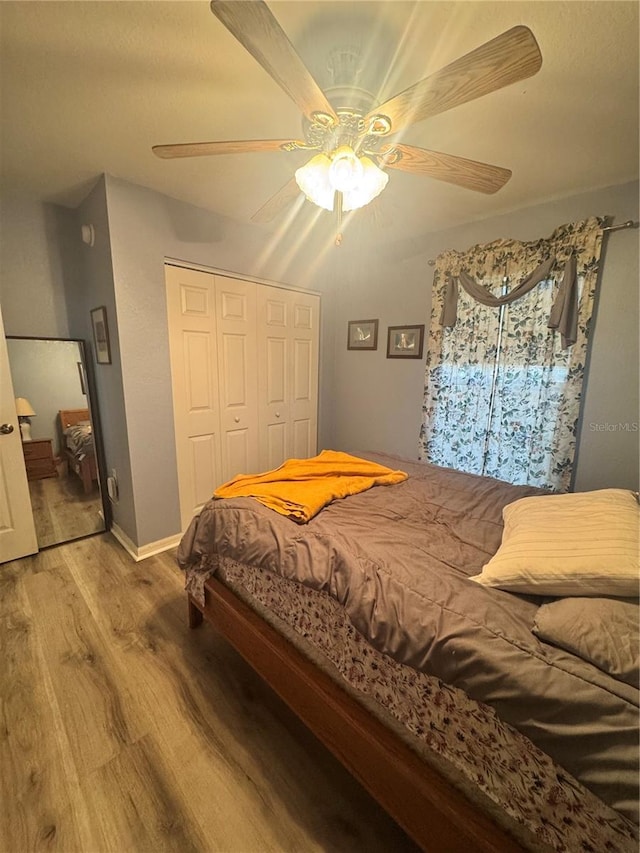 bedroom with a closet, wood finished floors, a ceiling fan, and baseboards