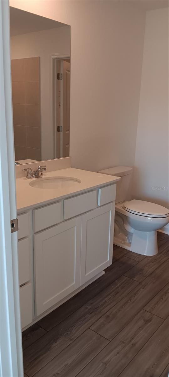 bathroom with vanity, toilet, and wood finished floors