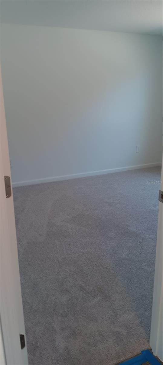 unfurnished room with carpet and baseboards