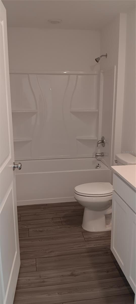 full bathroom with toilet, washtub / shower combination, wood finished floors, and vanity