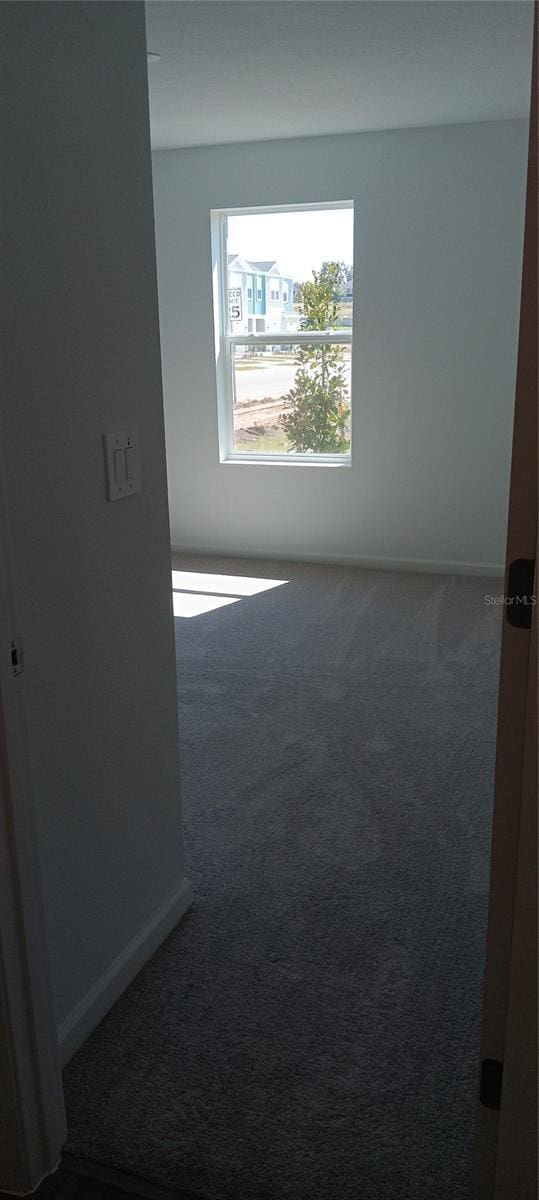 carpeted empty room with baseboards