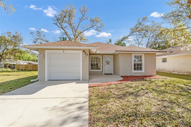 ranch-style home featuring an attached garage, fence, driveway, stucco siding, and a front lawn