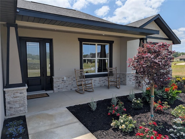property entrance with covered porch, roof with shingles, stucco siding, and stone siding