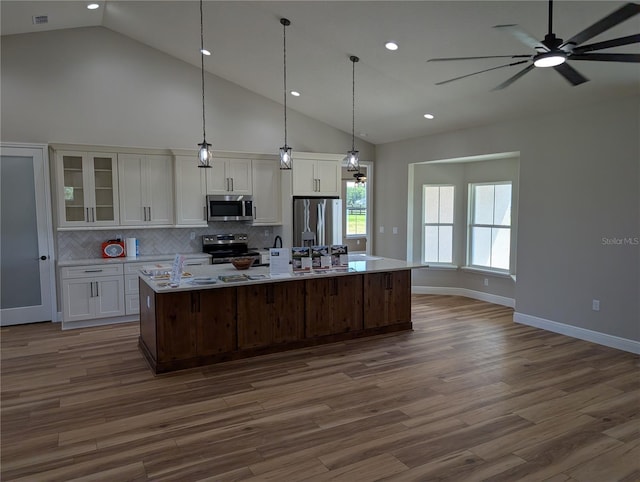 kitchen with recessed lighting, an island with sink, appliances with stainless steel finishes, white cabinets, and dark wood-style flooring