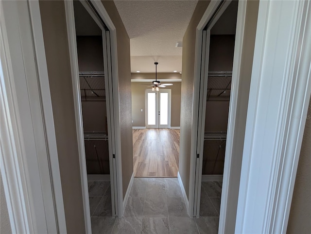 corridor featuring a textured ceiling and baseboards