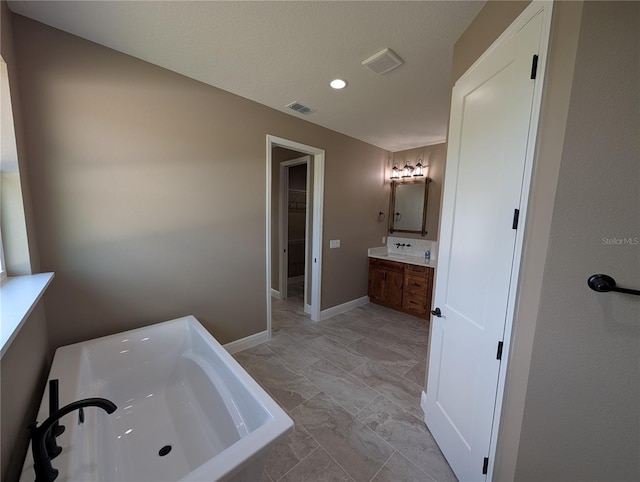 full bathroom with a bathing tub, a spacious closet, visible vents, baseboards, and vanity