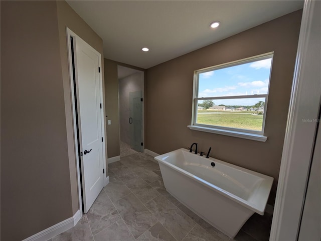 full bath featuring a stall shower, marble finish floor, a freestanding bath, and baseboards