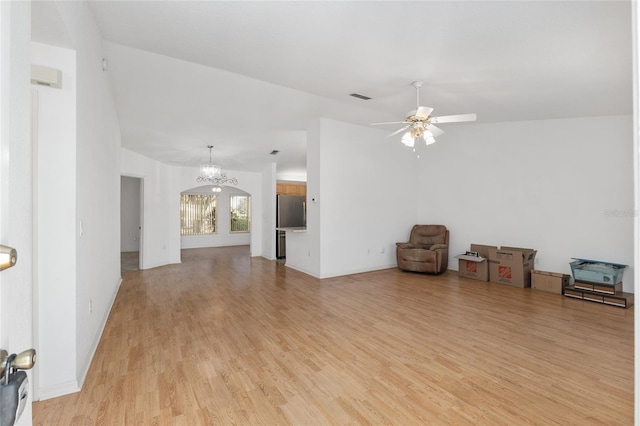 unfurnished living room with baseboards, visible vents, lofted ceiling, ceiling fan with notable chandelier, and light wood-type flooring