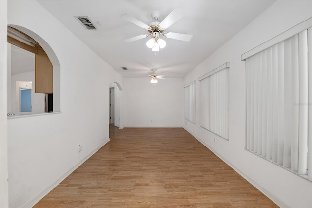 unfurnished room featuring arched walkways, visible vents, light wood finished floors, and ceiling fan