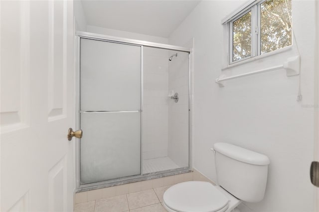 bathroom featuring tile patterned flooring, a shower stall, and toilet