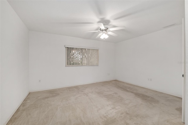 carpeted spare room with visible vents and a ceiling fan