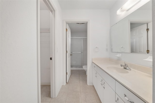 full bathroom with vanity, a stall shower, a spacious closet, tile patterned floors, and toilet