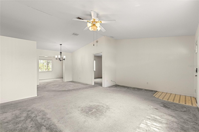 empty room featuring lofted ceiling, ceiling fan with notable chandelier, visible vents, and light colored carpet