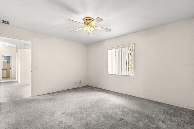 carpeted empty room featuring a ceiling fan, visible vents, and a textured ceiling