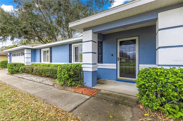 property entrance with a garage and stucco siding