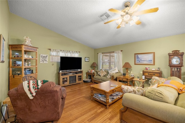 living room with lofted ceiling, visible vents, ceiling fan, a textured ceiling, and light wood-type flooring