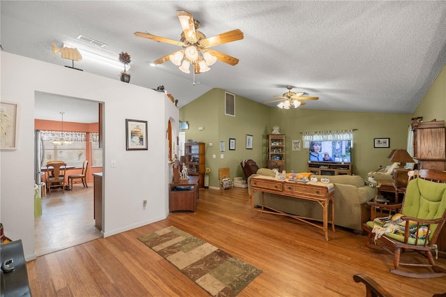 living area featuring light wood-type flooring, visible vents, and lofted ceiling