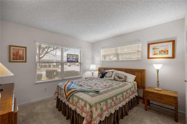 bedroom featuring light colored carpet, a textured ceiling, and baseboards