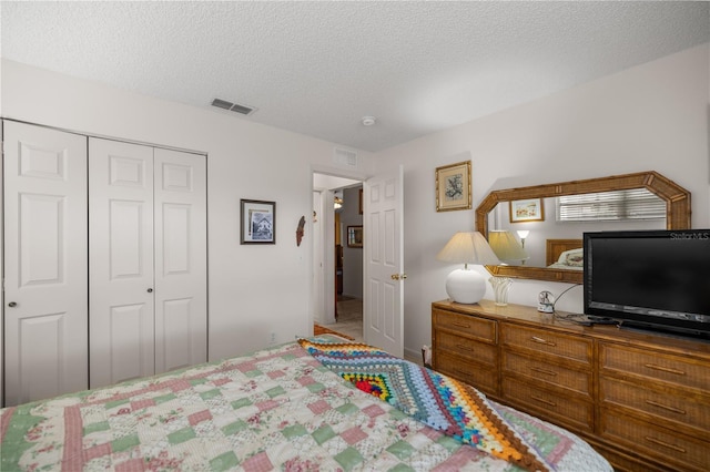 bedroom with a textured ceiling, a closet, and visible vents