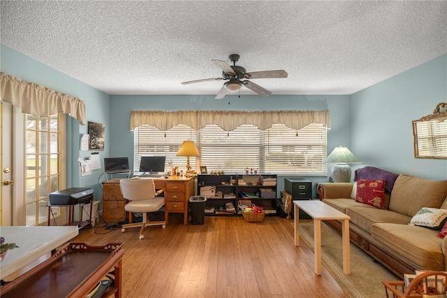 office area with a ceiling fan, a wealth of natural light, a textured ceiling, and hardwood / wood-style flooring