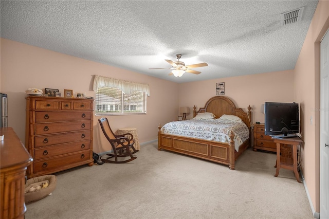 bedroom featuring a textured ceiling, visible vents, a ceiling fan, and light colored carpet