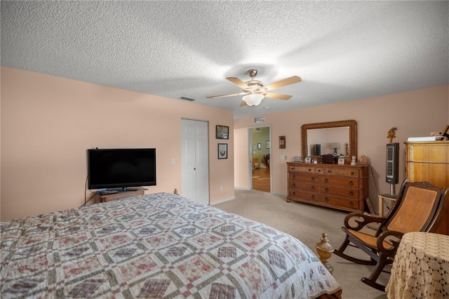 carpeted bedroom featuring a closet, visible vents, ceiling fan, and a textured ceiling