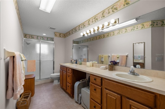 bathroom with double vanity, a stall shower, a textured ceiling, and a sink