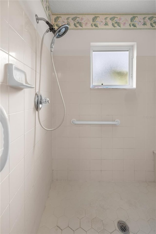 bathroom with a textured ceiling and tiled shower